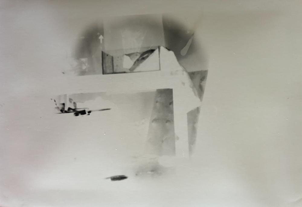 Pinhole photograph: a faint, pale interior with angled shapes inside a soft circular vignette