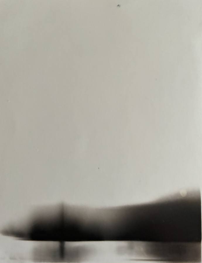 Pinhole photograph: a pale sky above a dark blurred horizon with a single post