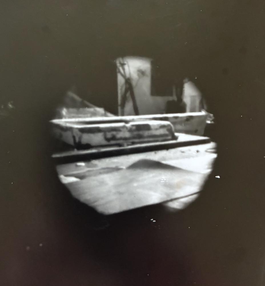 Pinhole photograph: a workshop interior seen through a soft dark circle, with a bench and tools in the light
